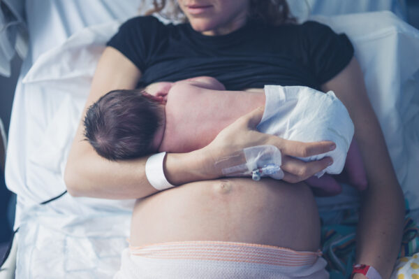 Mother in a hospital bed, holding her newborn baby.